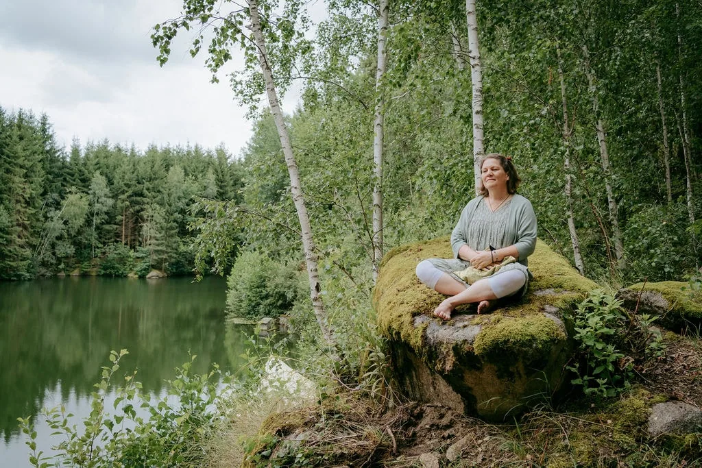 Simone Wampfler meditiert auf einem Stein am See